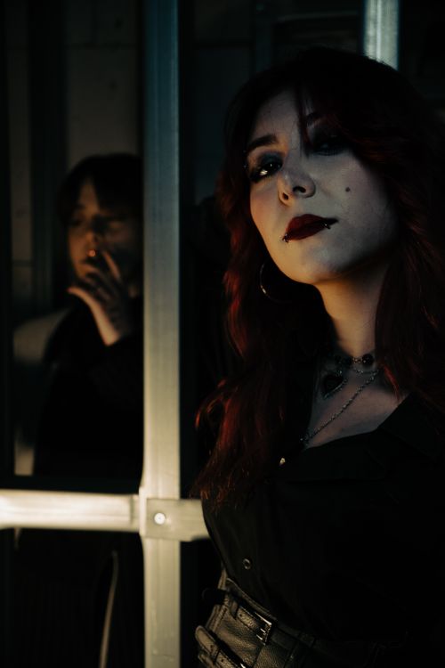 Free A woman with bold makeup stands in dim lighting, creating a mysterious atmosphere. Stock Photo