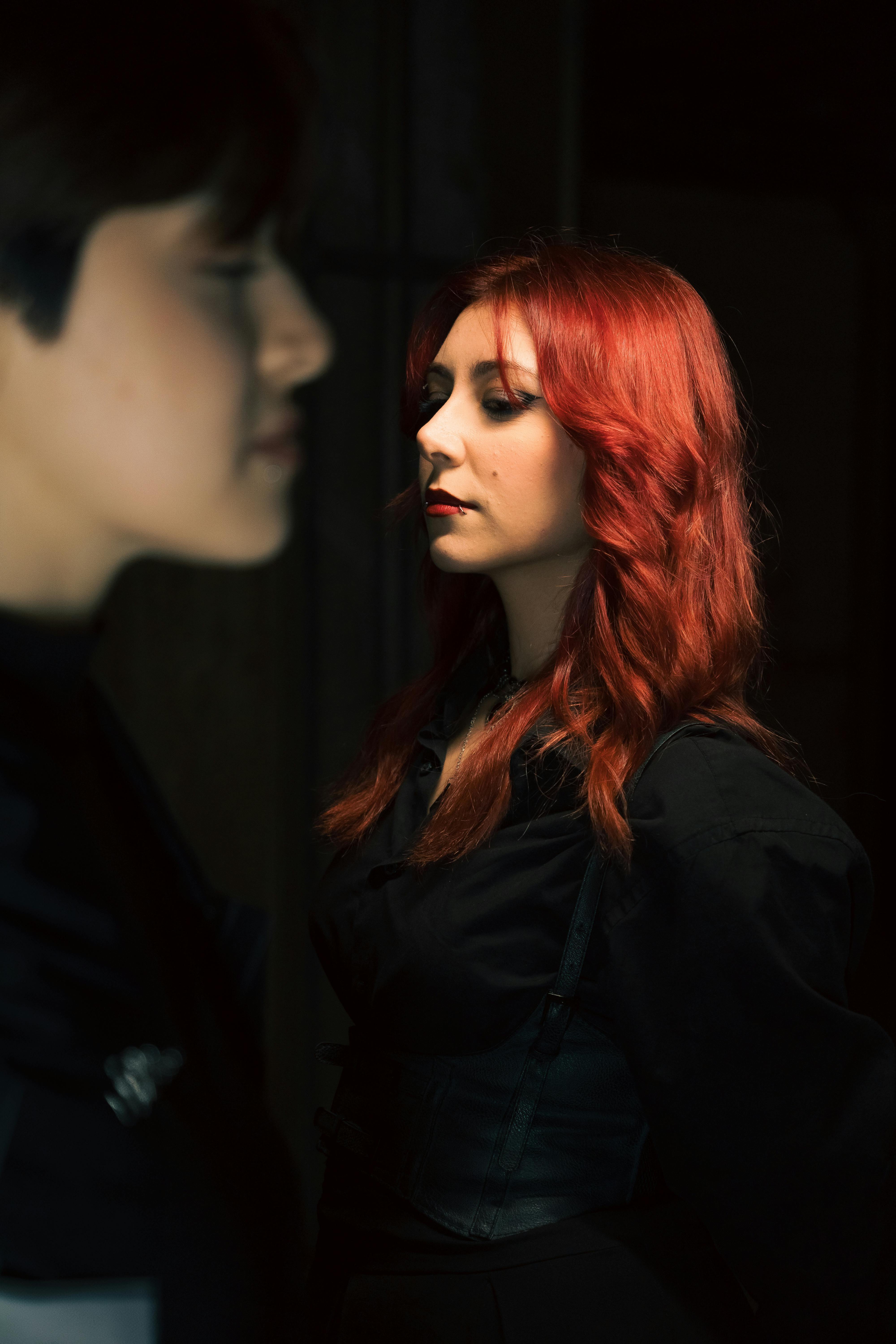 Artistic portrait of two individuals in dramatic lighting, focusing on red hair.