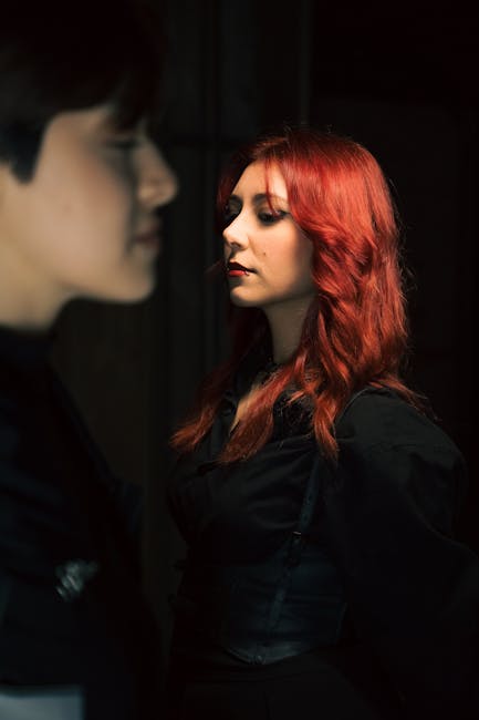 Artistic portrait of two individuals in dramatic lighting, focusing on red hair.