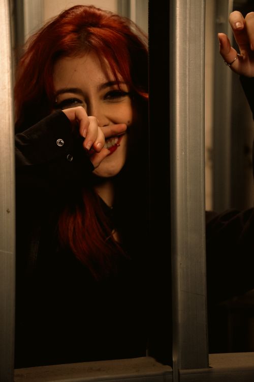 Free Warm portrait of a smiling young woman with red hair in a dimly lit room. Stock Photo