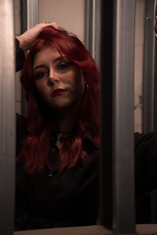 Free A dramatic portrait of a woman with red hair in a dimly lit room. Stock Photo