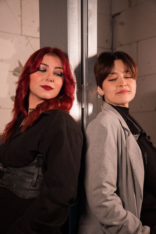 Free Two stylish adults standing back-to-back with eyes closed against a mirrored surface. Stock Photo