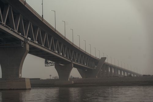 Free A broad, modern bridge spanning over a calm river at dusk in Madaripur, Bangladesh. Stock Photo