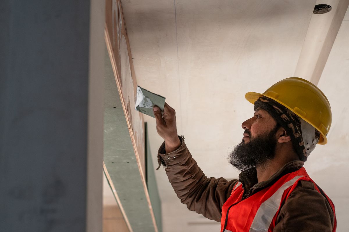 Builder plastering and smoothing an interior wall during a domestic building project