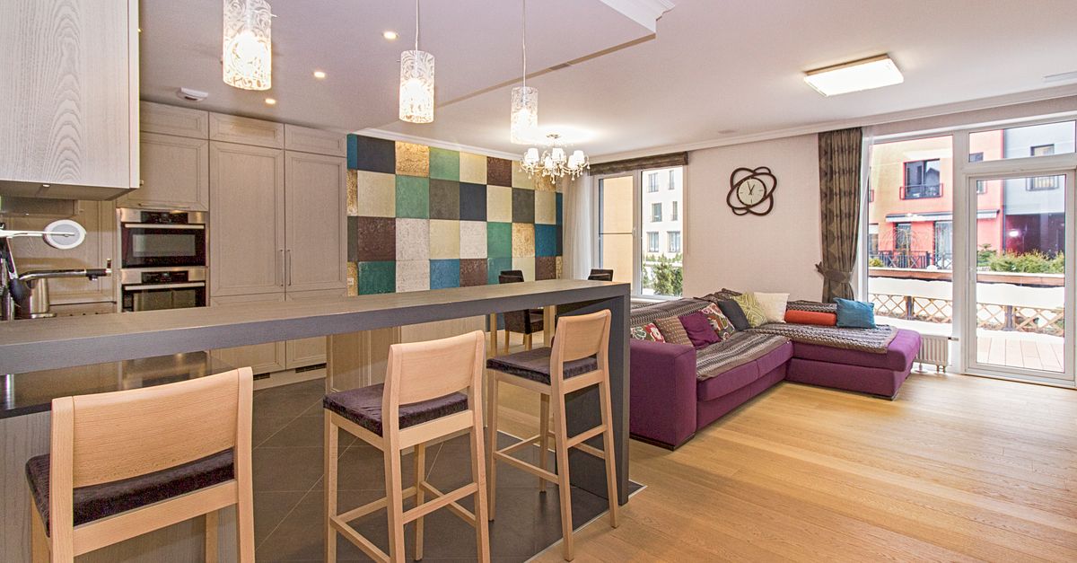 Stylish open-plan kitchen and living room with modern decor and ample lighting.