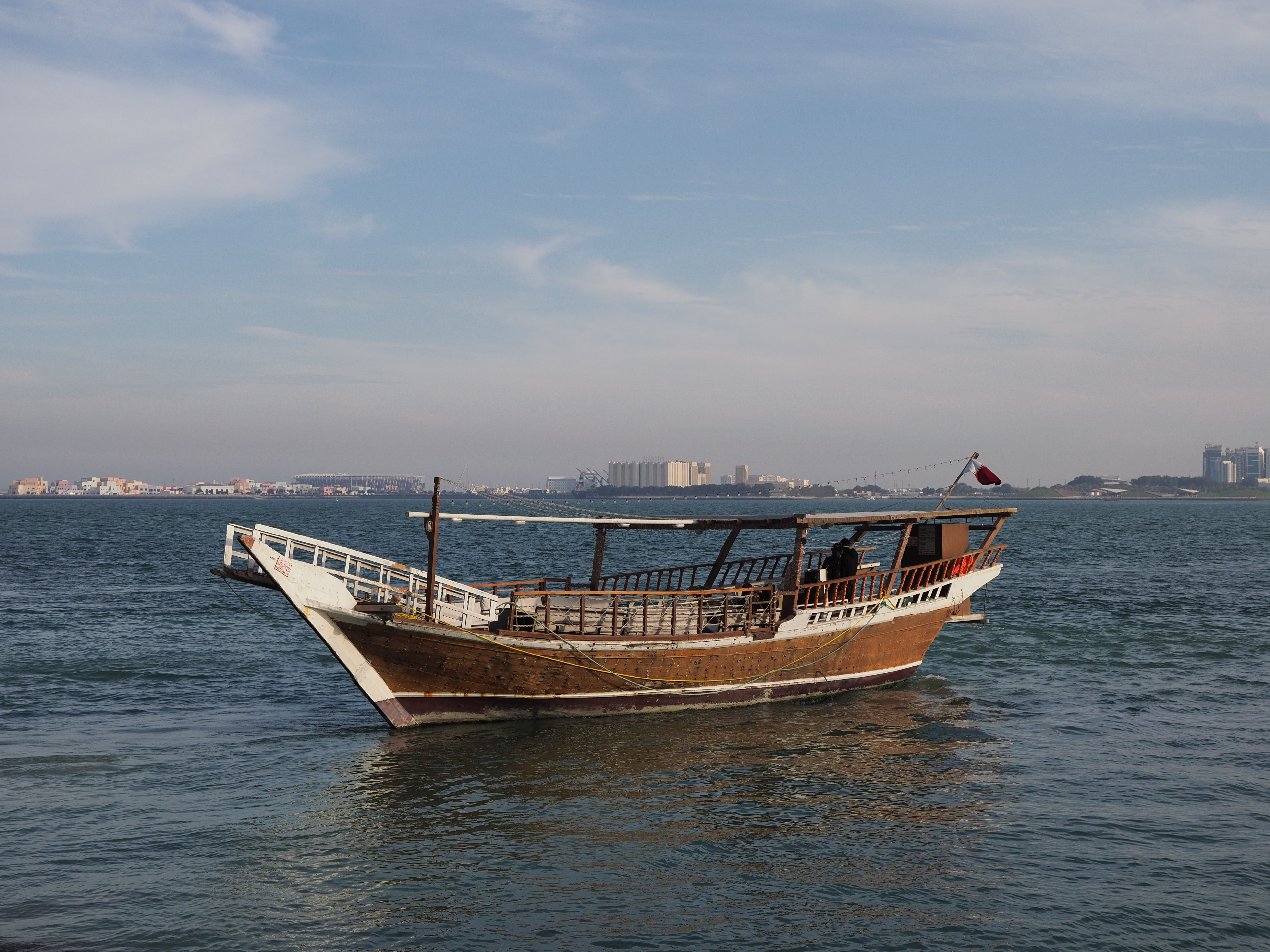 Traditional Dhow boat cruising along the Doha Corniche in Qatar at sunset