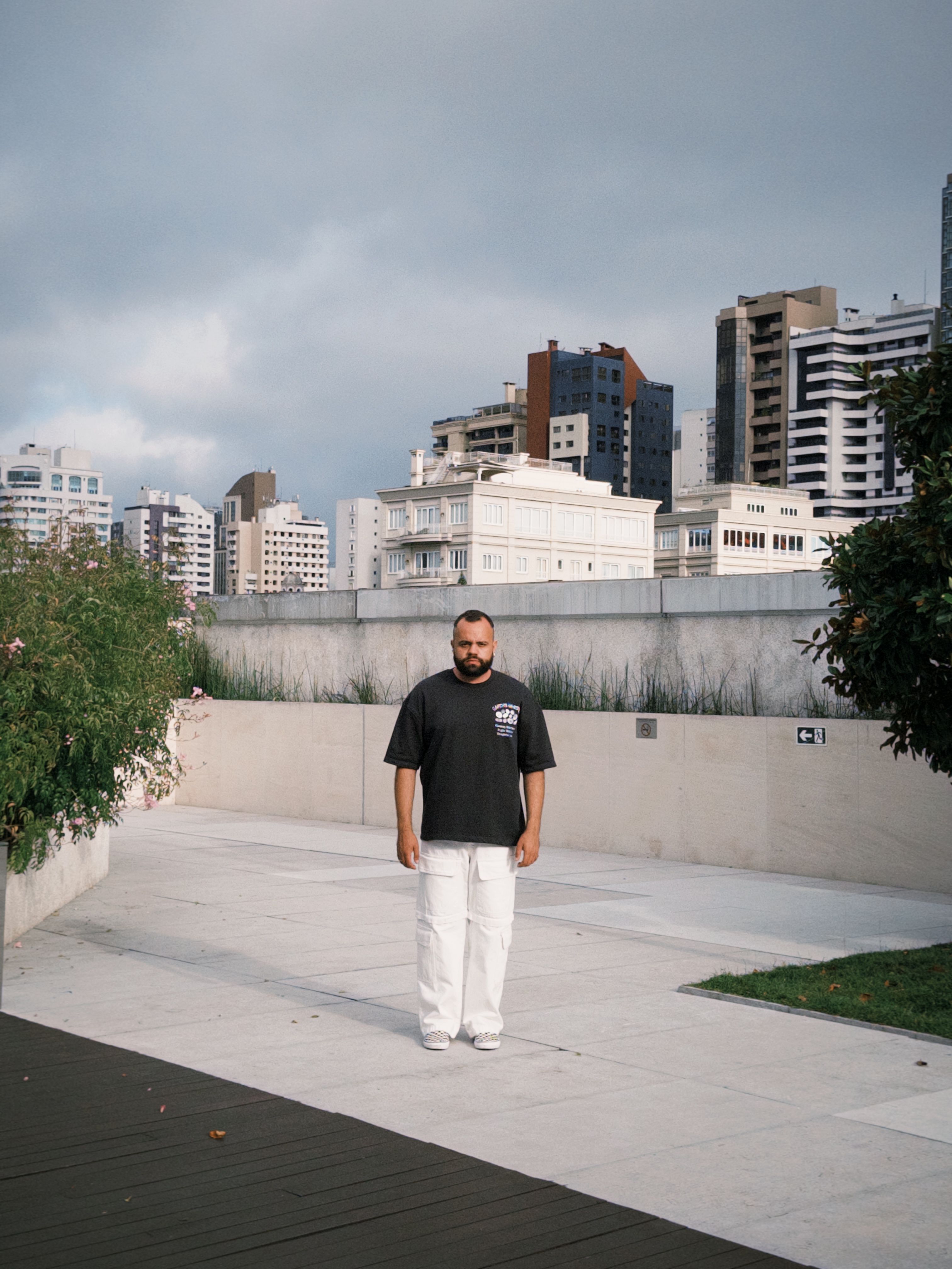 A man standing outside in a Curitiba cityscape, showcasing modern Brazilian architecture.