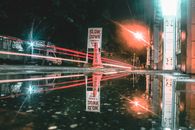 夜晚的城市街道上，水坑反射着路灯的光径
