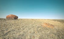 广阔的干燥景观中，独特的红石与清澈的蓝天交相辉映，展现出自然的壮美