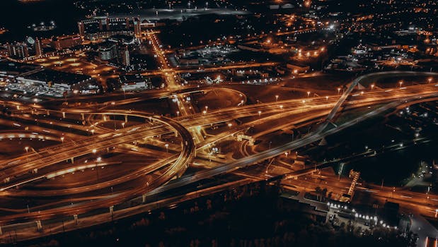 Dramatic aerial shot of city highways and lights at night, showcasing urban infrastructure.