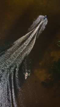 Stunning aerial capture of a speedboat creating waves on a calm lake, perfect for travel and adventure themes.