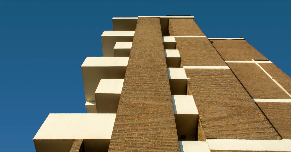 Low angle view of a modern brick and concrete building with clear blue sky background.