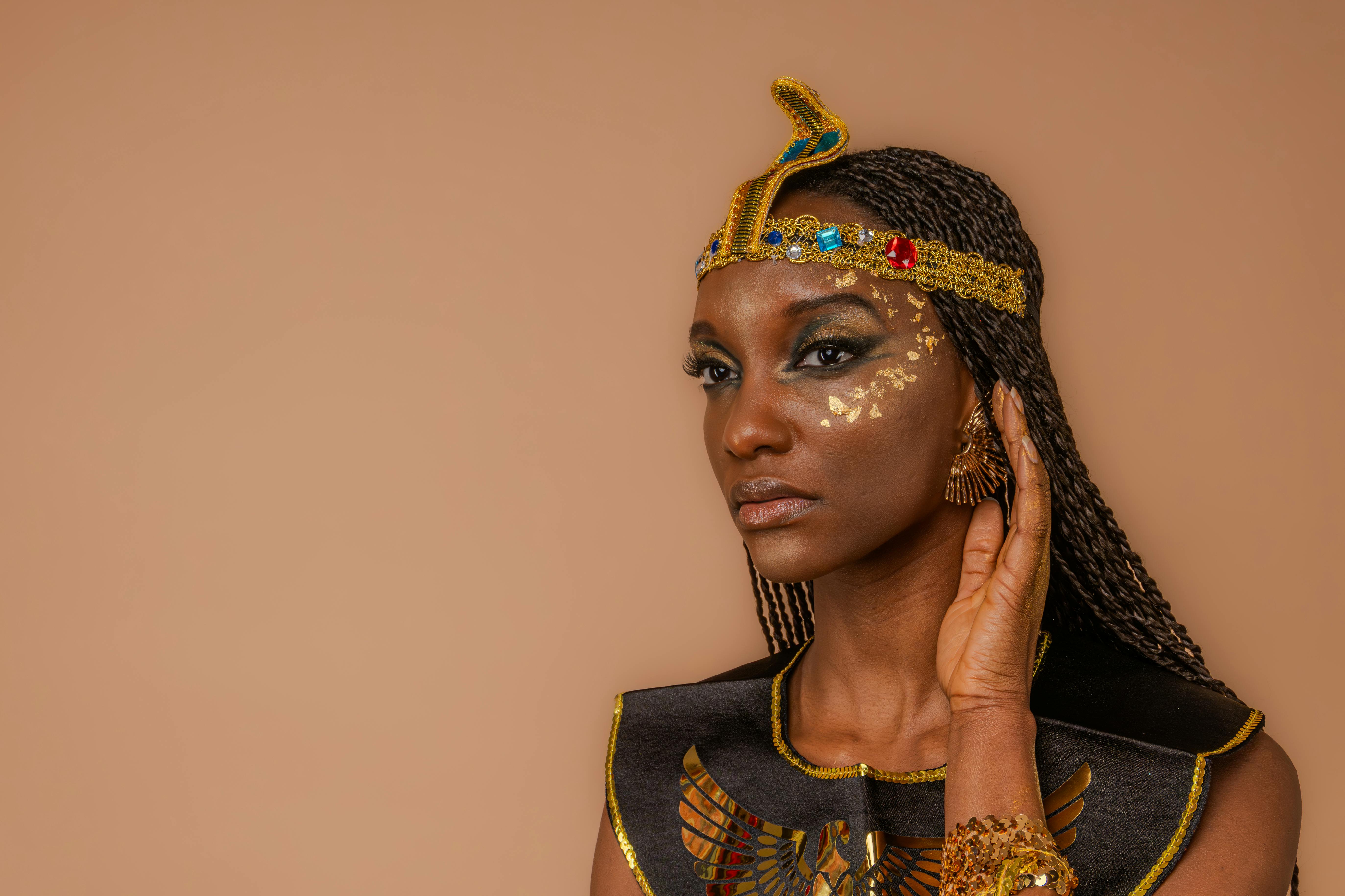 Beautiful portrait of a woman in Egyptian-inspired attire with creative makeup and jewelry.