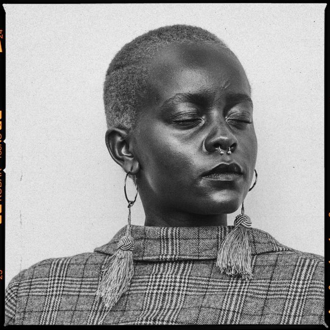 A striking black and white portrait of an elegant African woman with stylish earrings and nose piercing.