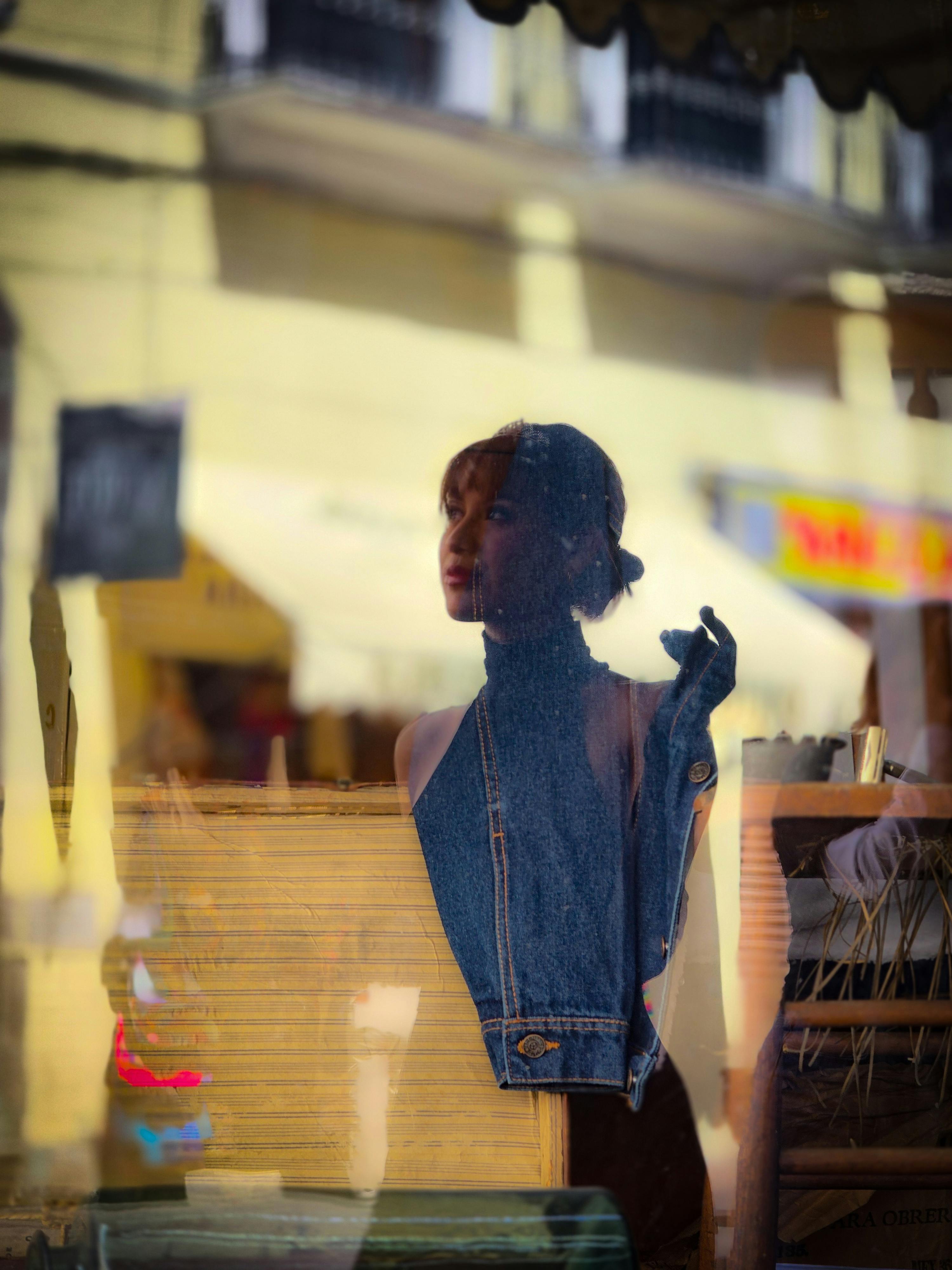 Ücretsiz Kot kumaştan bir mankenin ve yansıtıcı kentsel bir arka planın yer aldığı sanatsal vitrin düzenlemesi. Stok Fotoğraflar