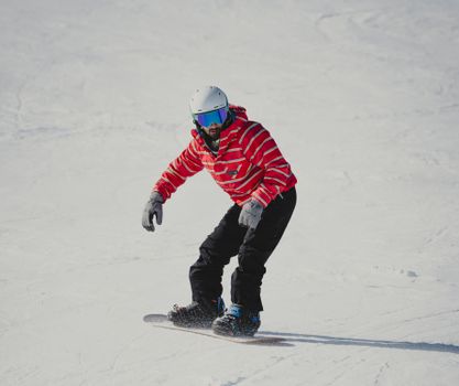 A snowboarder wearing a red jacket glides down a snowy slope, capturing winter adventure.