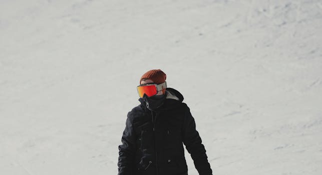 A snowboarder with goggles and beanie enjoying a ride on a snowy slope.