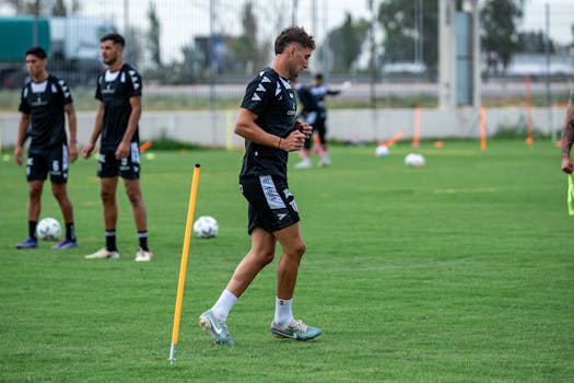 Soccer players training outdoors on a green field, focusing on drills and teamwork.