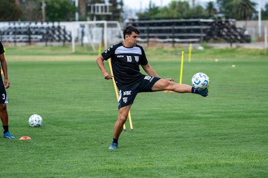A soccer player in action during training with a high kick on a green field.
