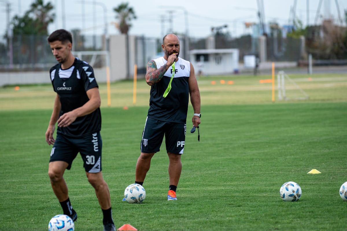 Allenatore concentrato istruisce giocatori durante allenamento su campo verde
