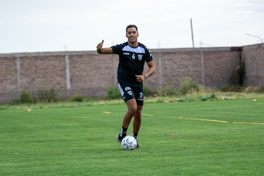 A young male soccer player practicing dribbling on an outdoor grass field.