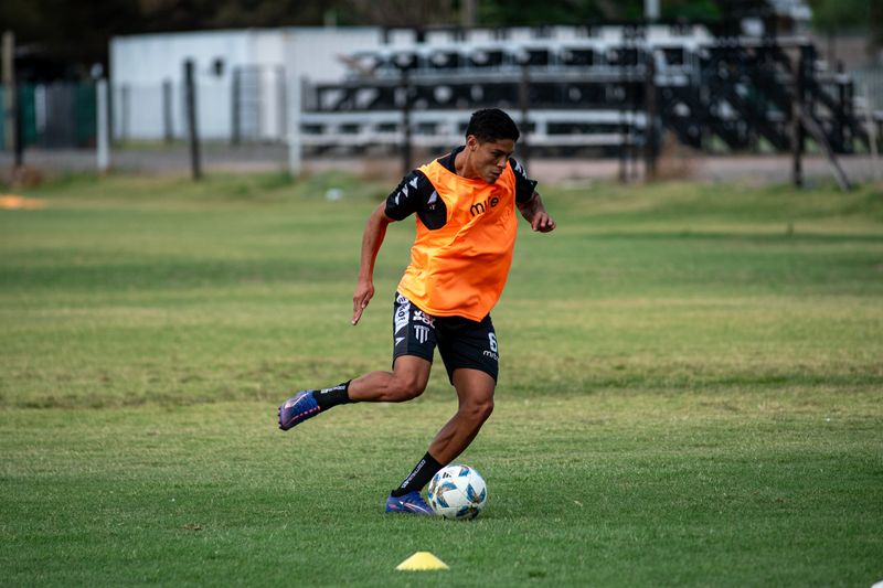 Academy player in an orange bib dribbling at training