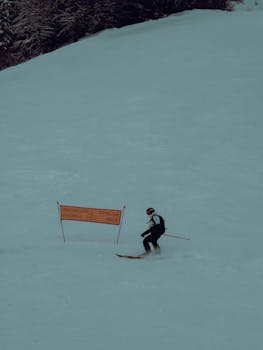 Skier gliding down snowy slope during wintertime, showcasing alpine skiing excitement.