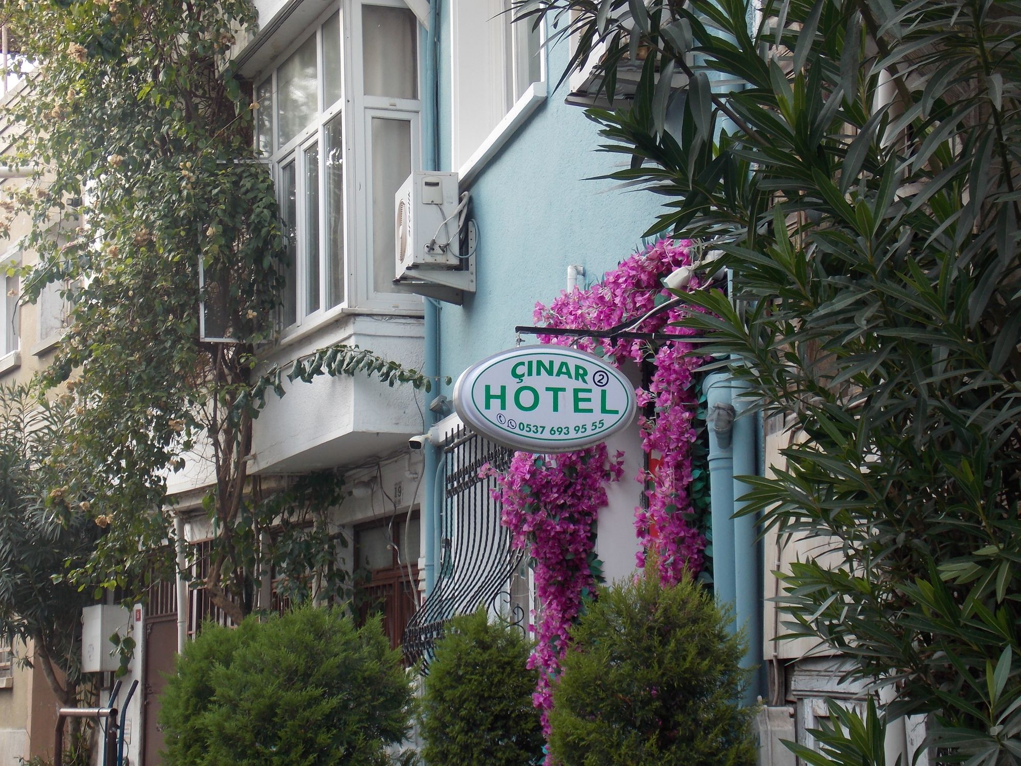 Exterior of a hotel adorned with vibrant pink flowers, set in an urban Istanbul street.