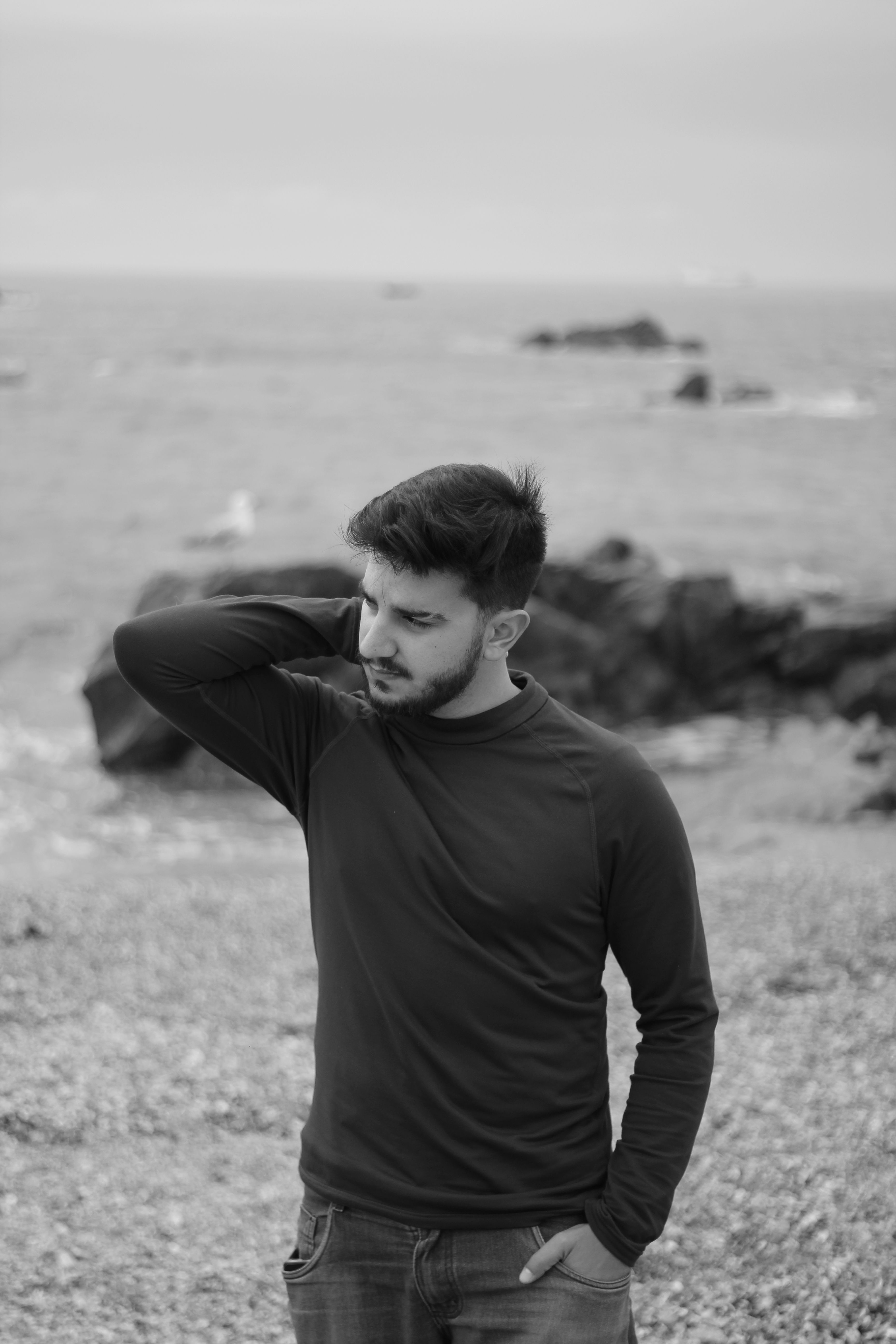 Black and white portrait of a man on a rocky beach in Porto, Portugal.