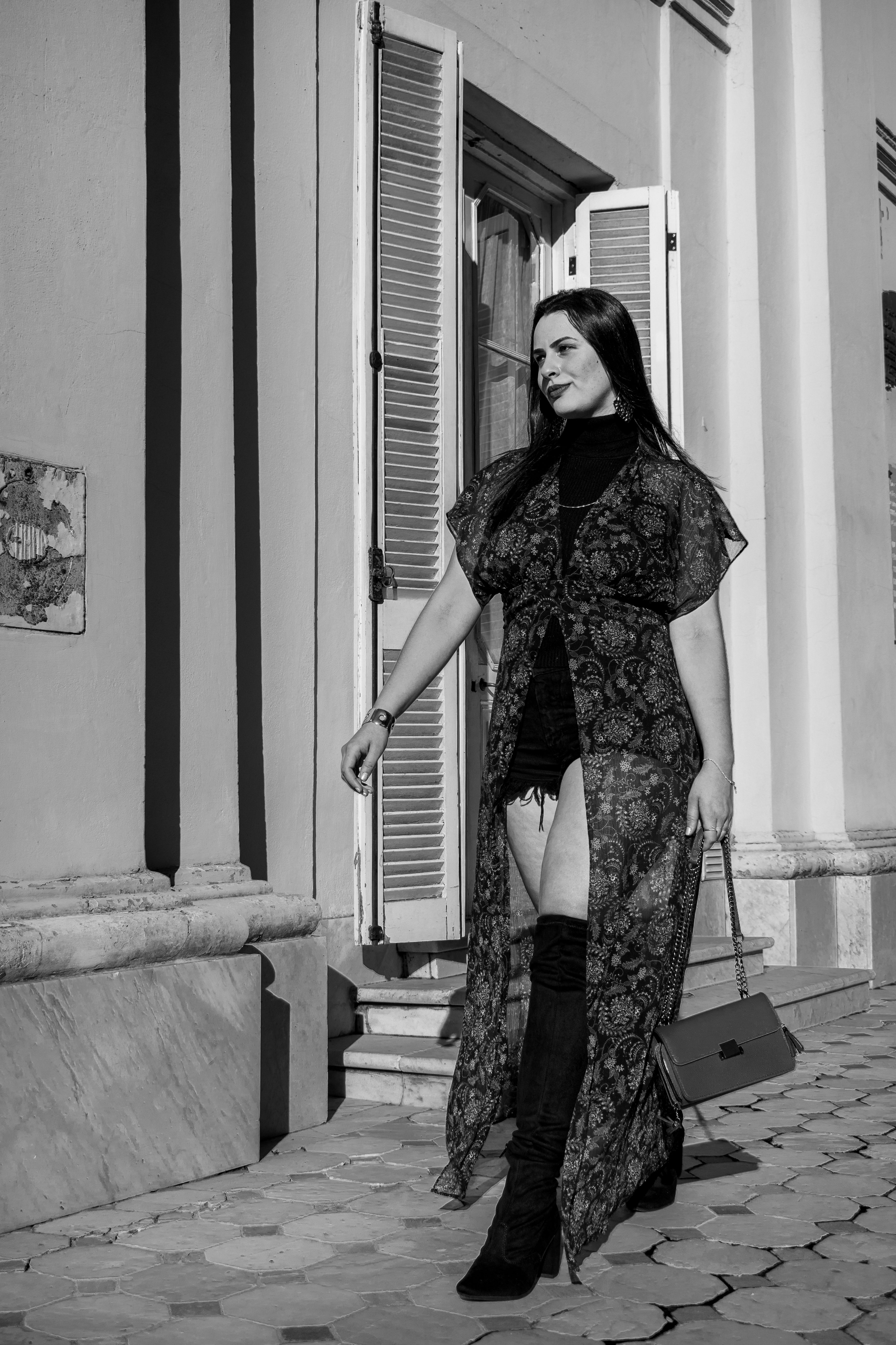 Black and white portrait of a stylish woman walking in Buenos Aires' urban landscape.