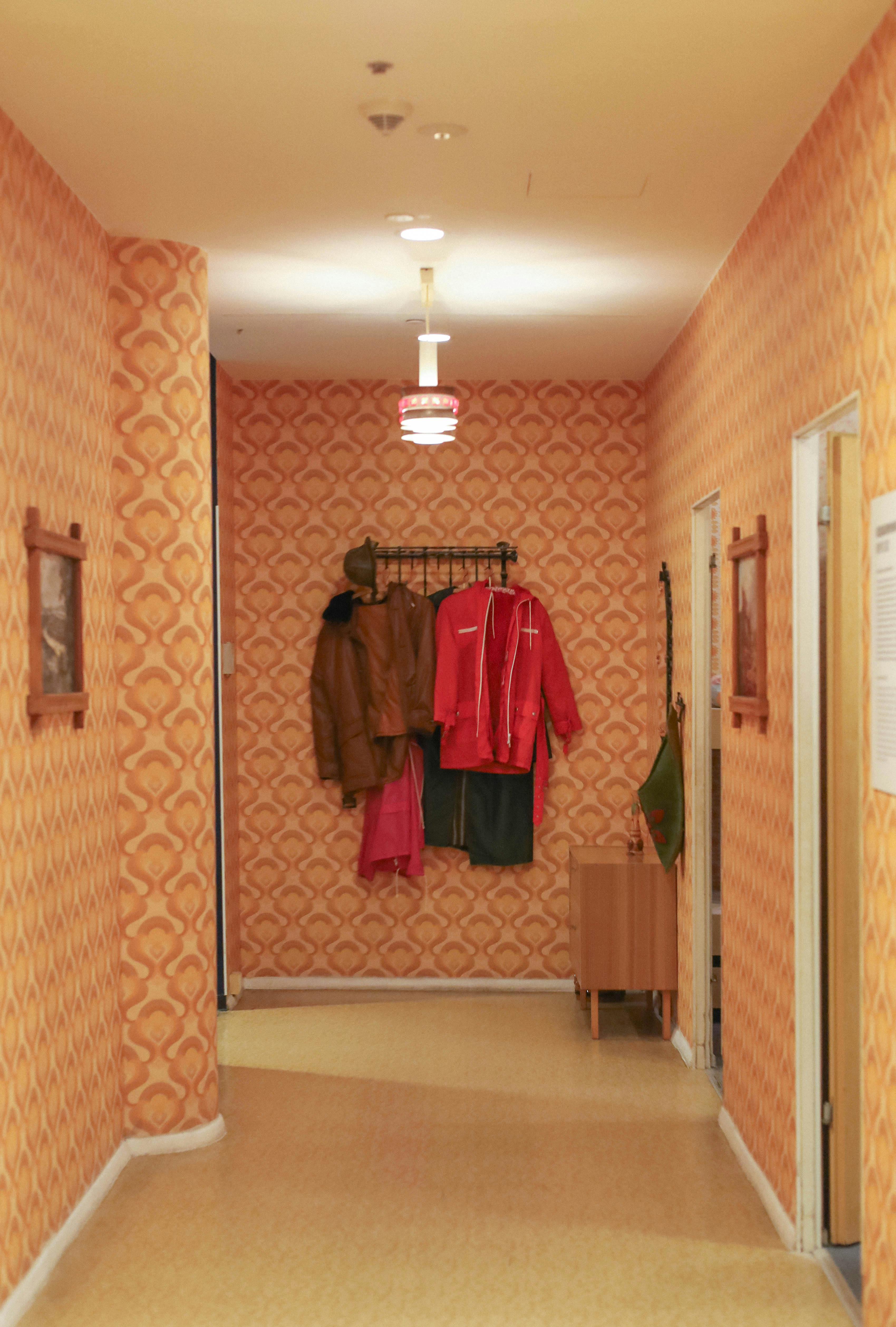 Kostnadsfria En vintage hall med retrotapeter och hängande rockar som utstrålar 70-talsnostalgi. Stock foto