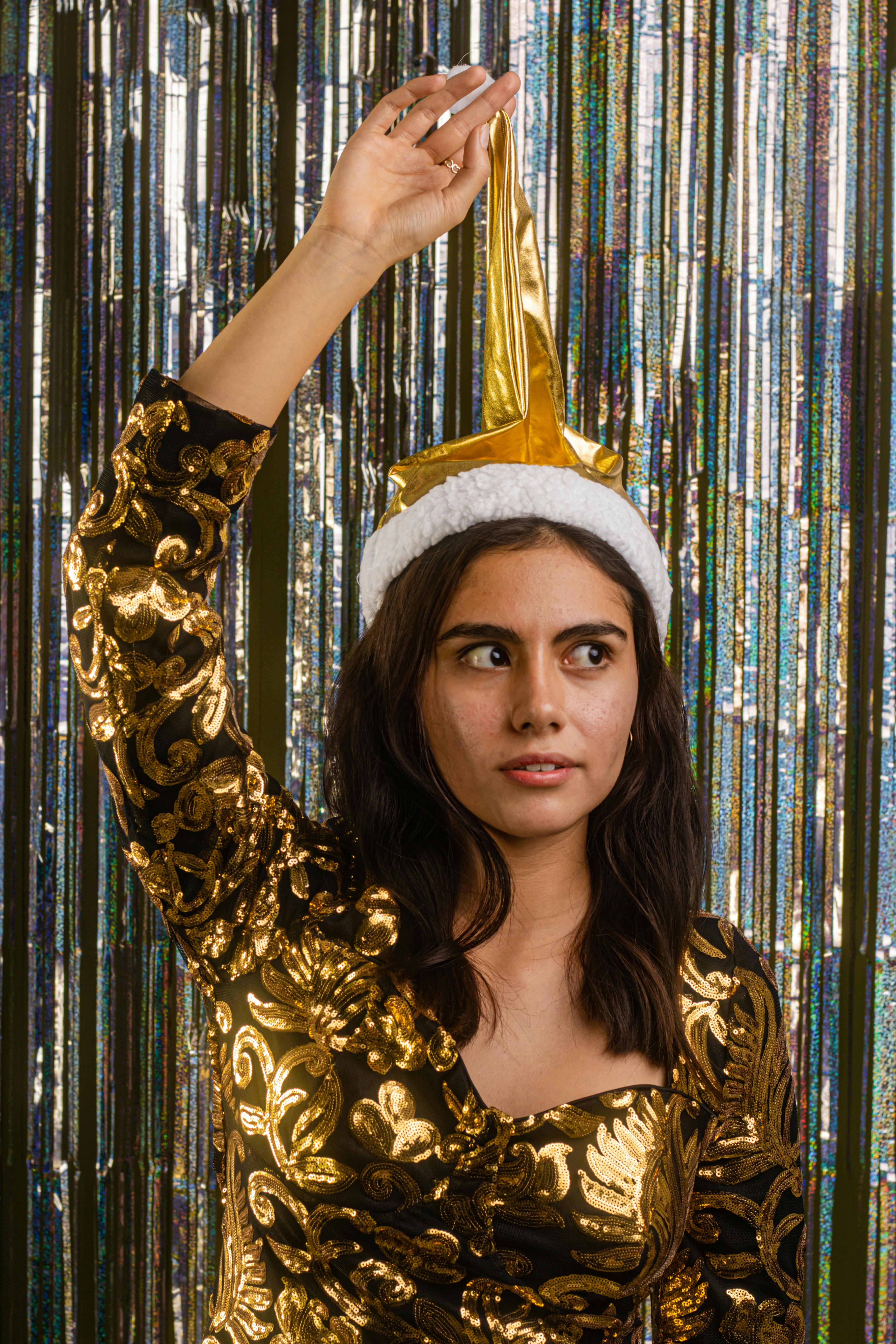 Woman in gold dress with Christmas hat against festive backdrop in Mexico City studio.