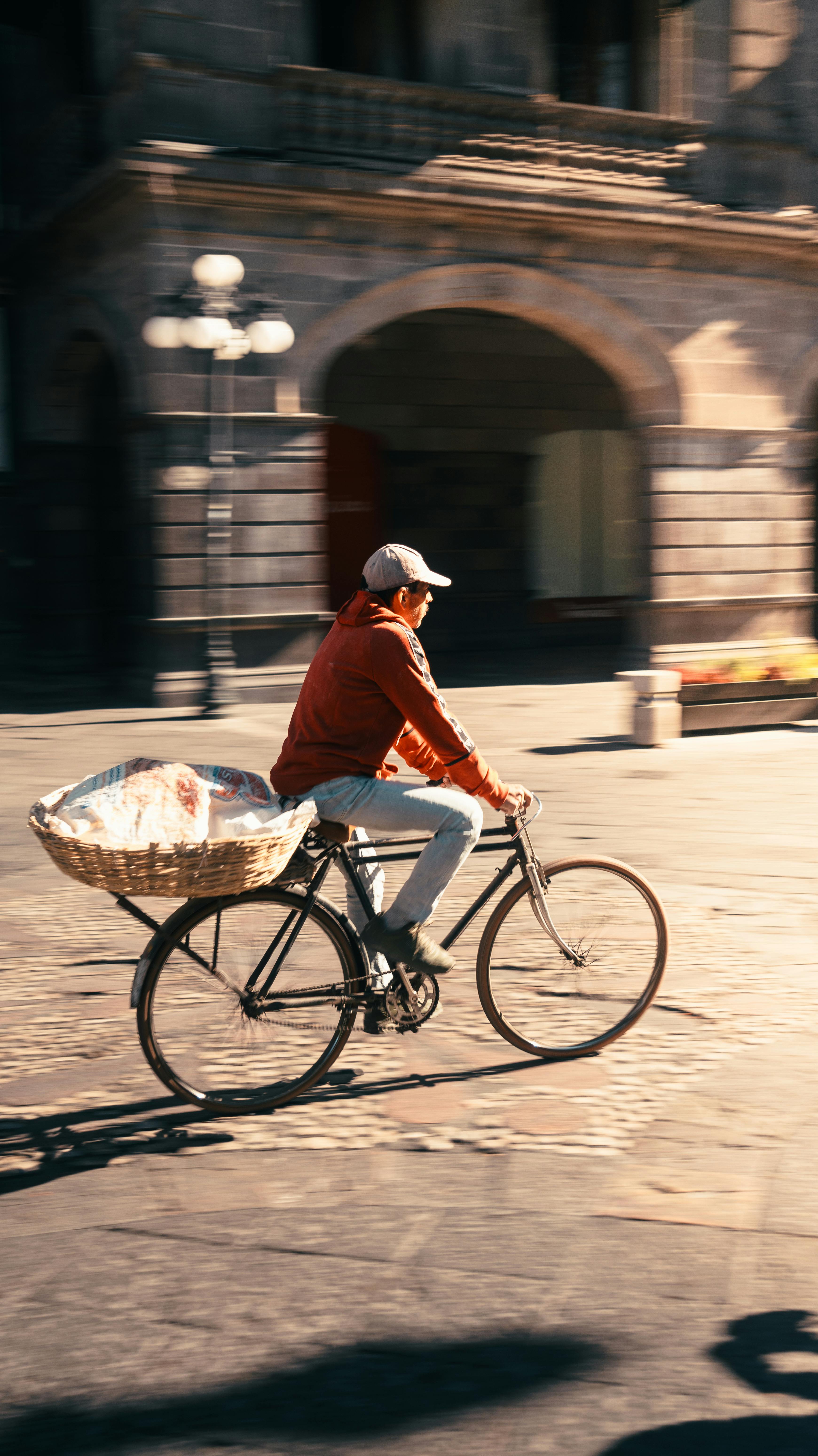 Man cycling through Puebla's streets carrying bread in basket. Vibrant city scene.