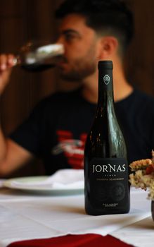 A sophisticated wine tasting moment with a focus on a premium wine bottle and blurred background ambiance.