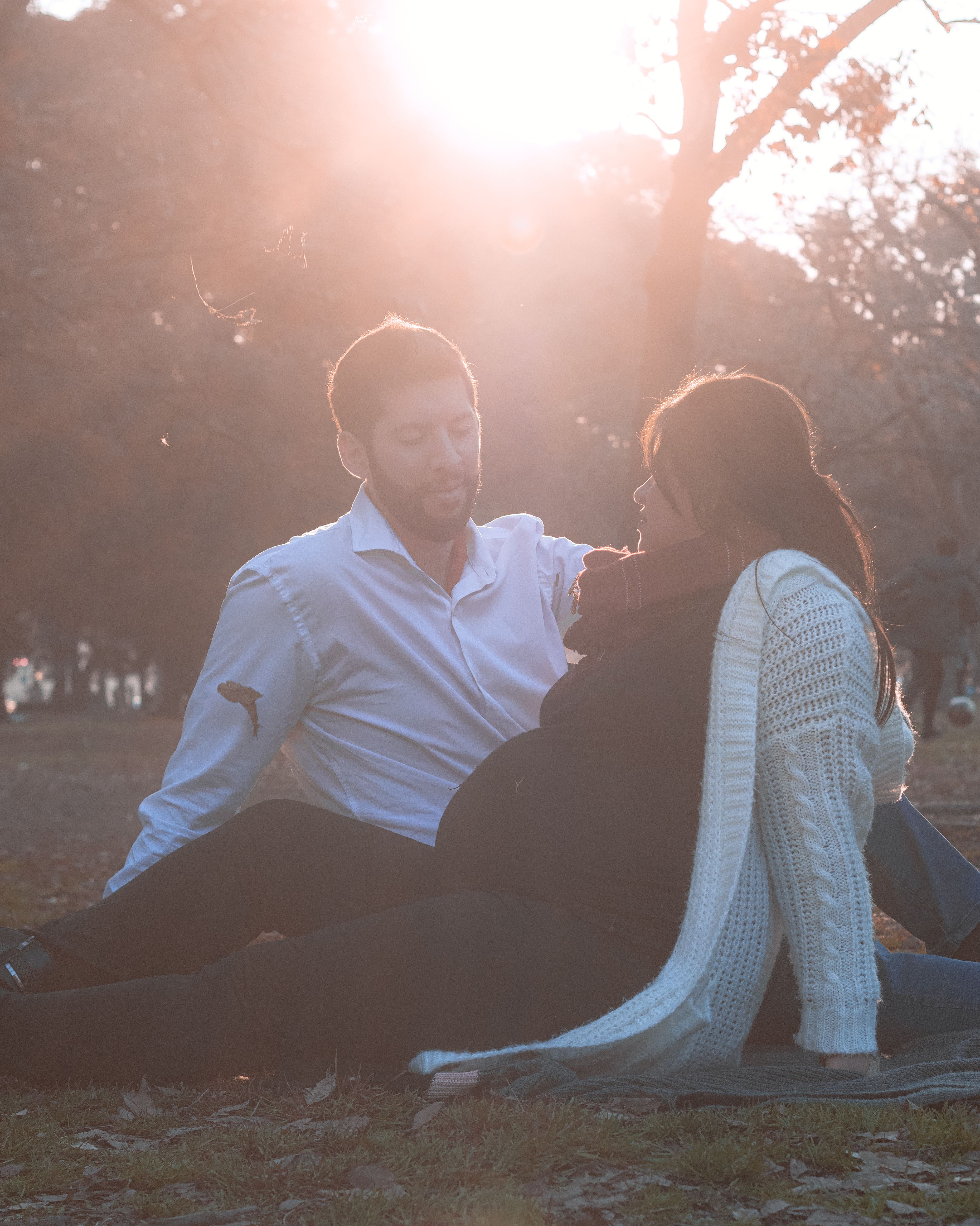 A loving moment shared by an expecting couple in a sunlit Buenos Aires park.