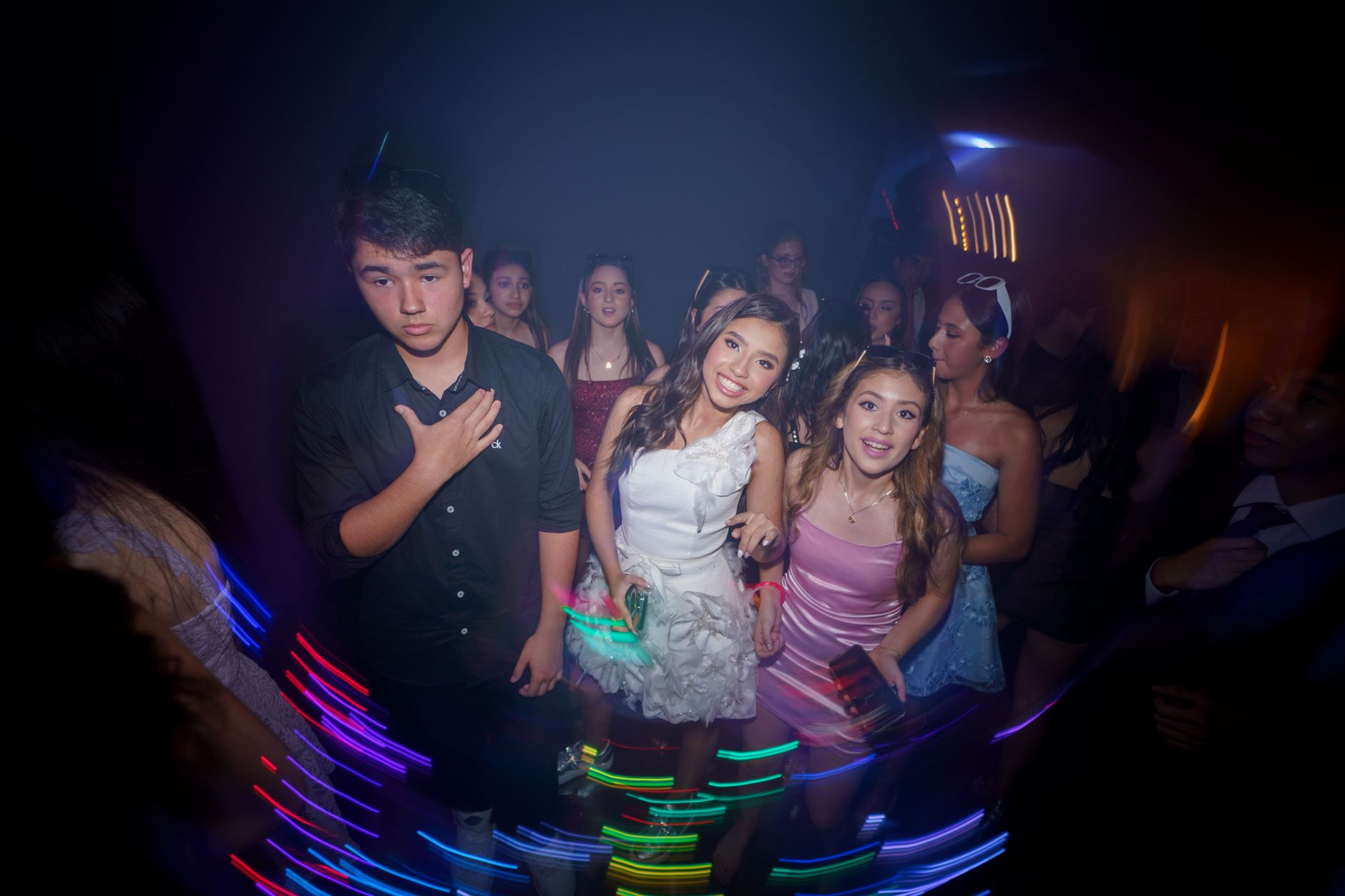 Group of teenagers having fun at a lively party with colorful lights.