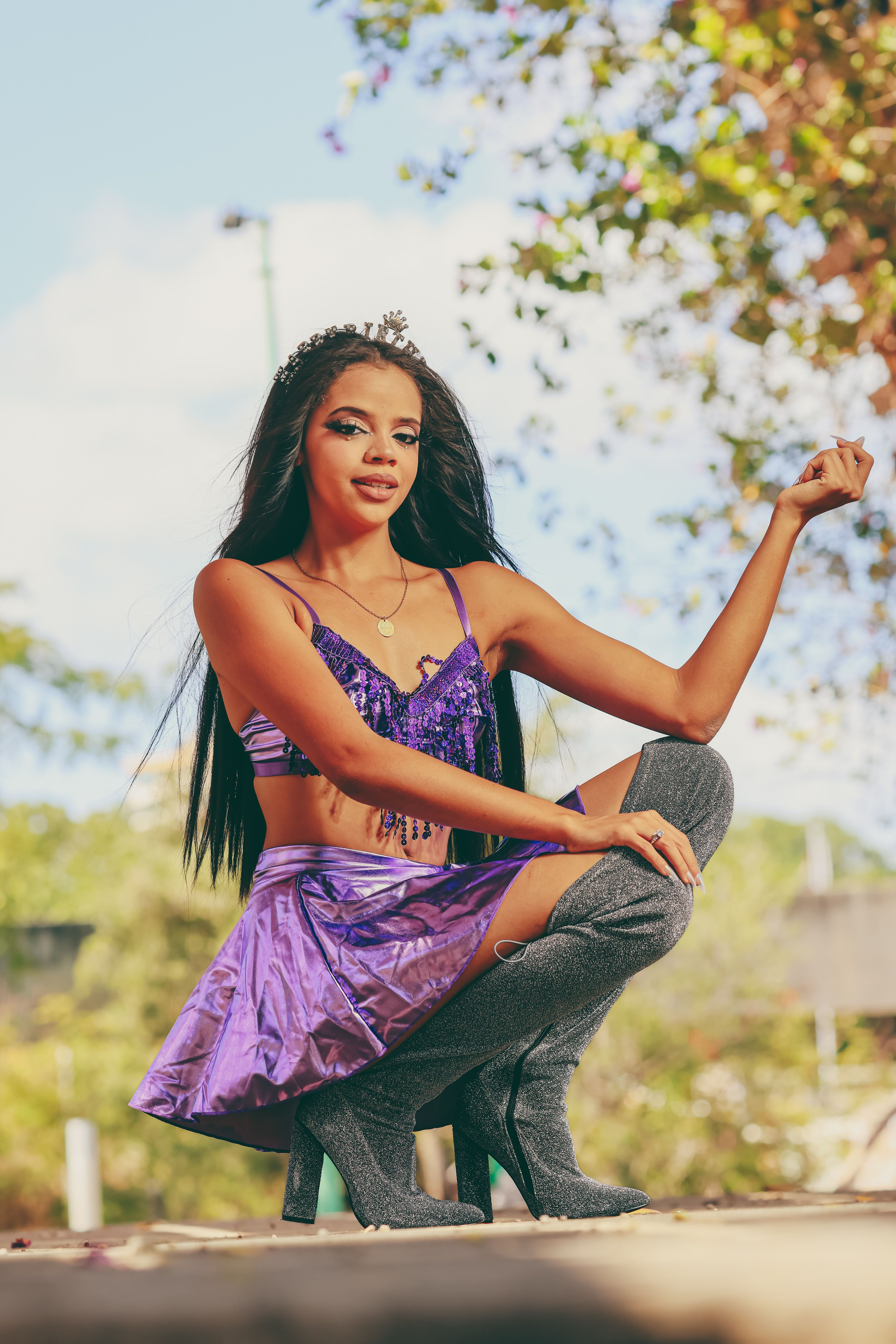 Stylish woman in a purple ensemble, posing confidently outdoors under the daylight.
