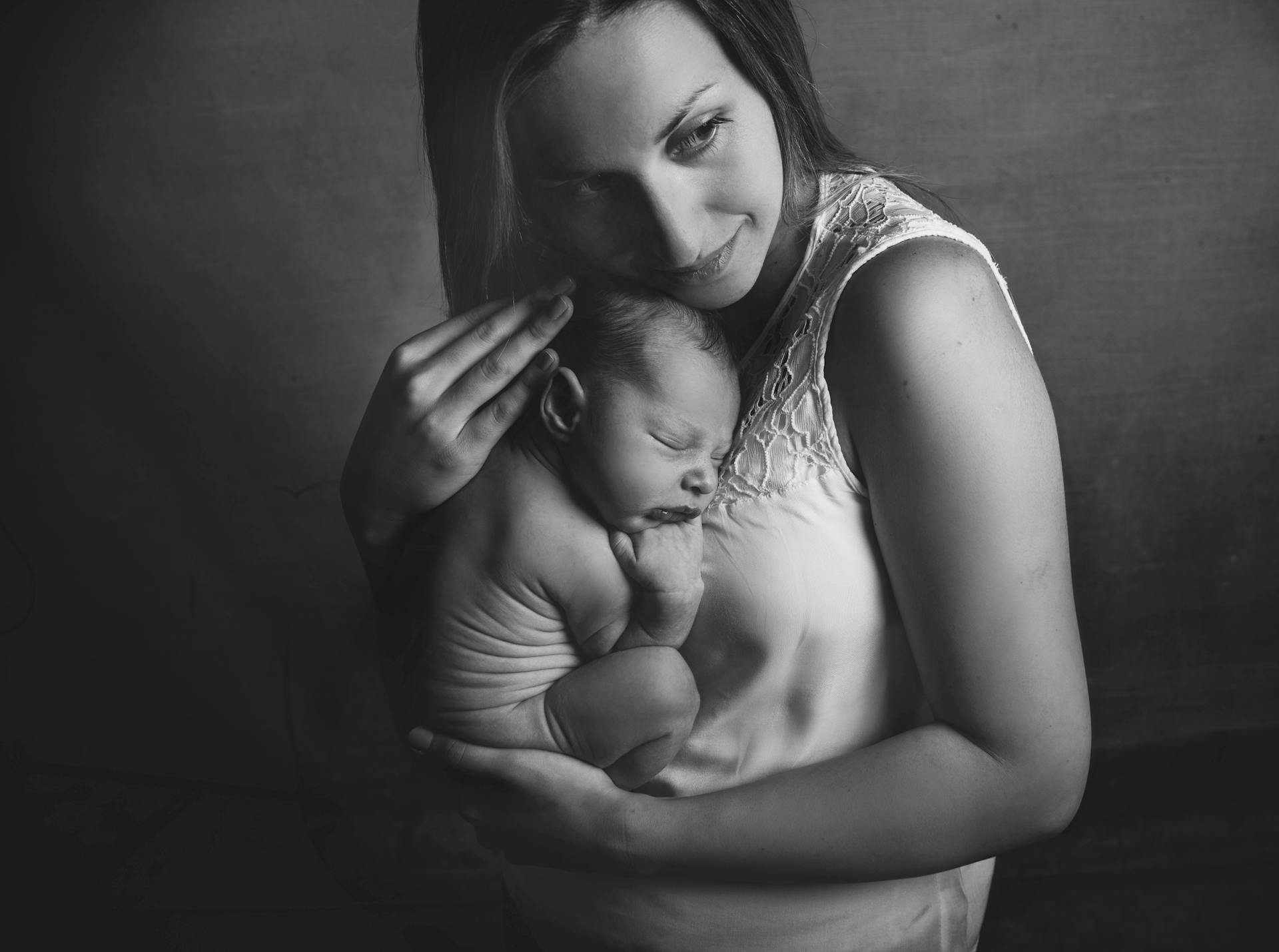 Black and white photo capturing a tender moment between a mother and her newborn baby.