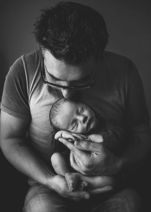 Free Heartwarming black and white image of a father cradling his newborn baby closely. Stock Photo