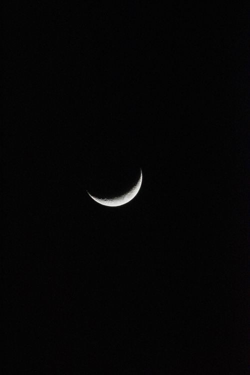 Free A beautiful crescent moon illuminated against a deep black night sky. Stock Photo