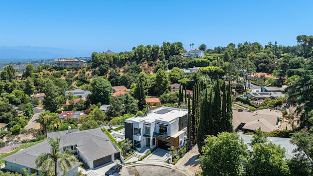 Aerial view of a luxurious residential area in sunny Los Angeles, surrounded by lush greenery and scenic landscapes.
