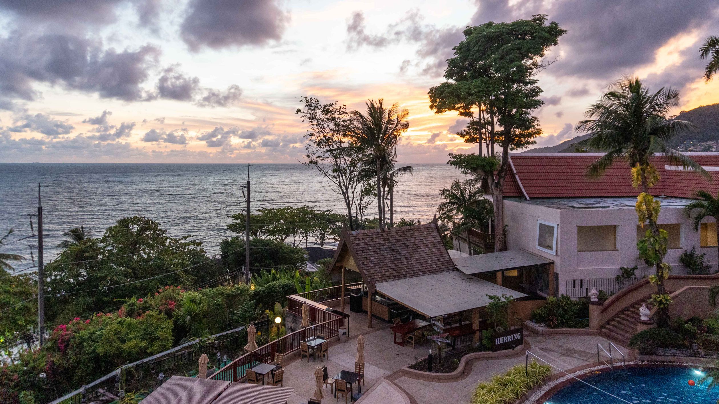 A breathtaking view of a coastal resort with lush greenery and ocean at sunset.
