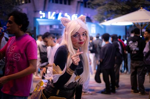 Free A cosplayer poses amidst a vibrant street crowd during a night event. Stock Photo