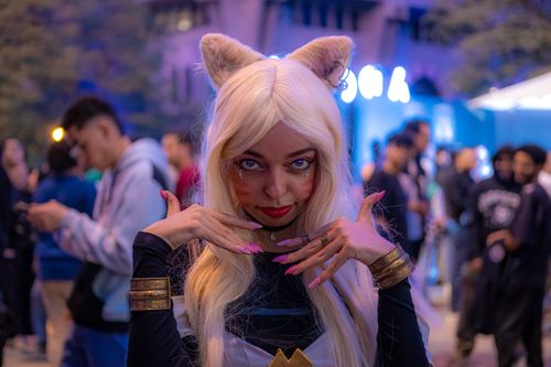 Free A woman in a cat-inspired costume poses playfully at a lively evening event. Stock Photo