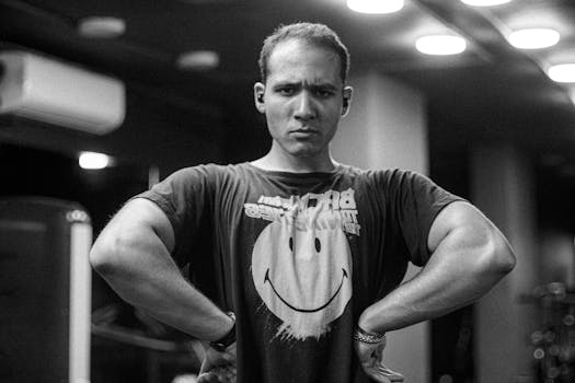 Focused man in gym wearing a smiley face t-shirt, captured in black and white.