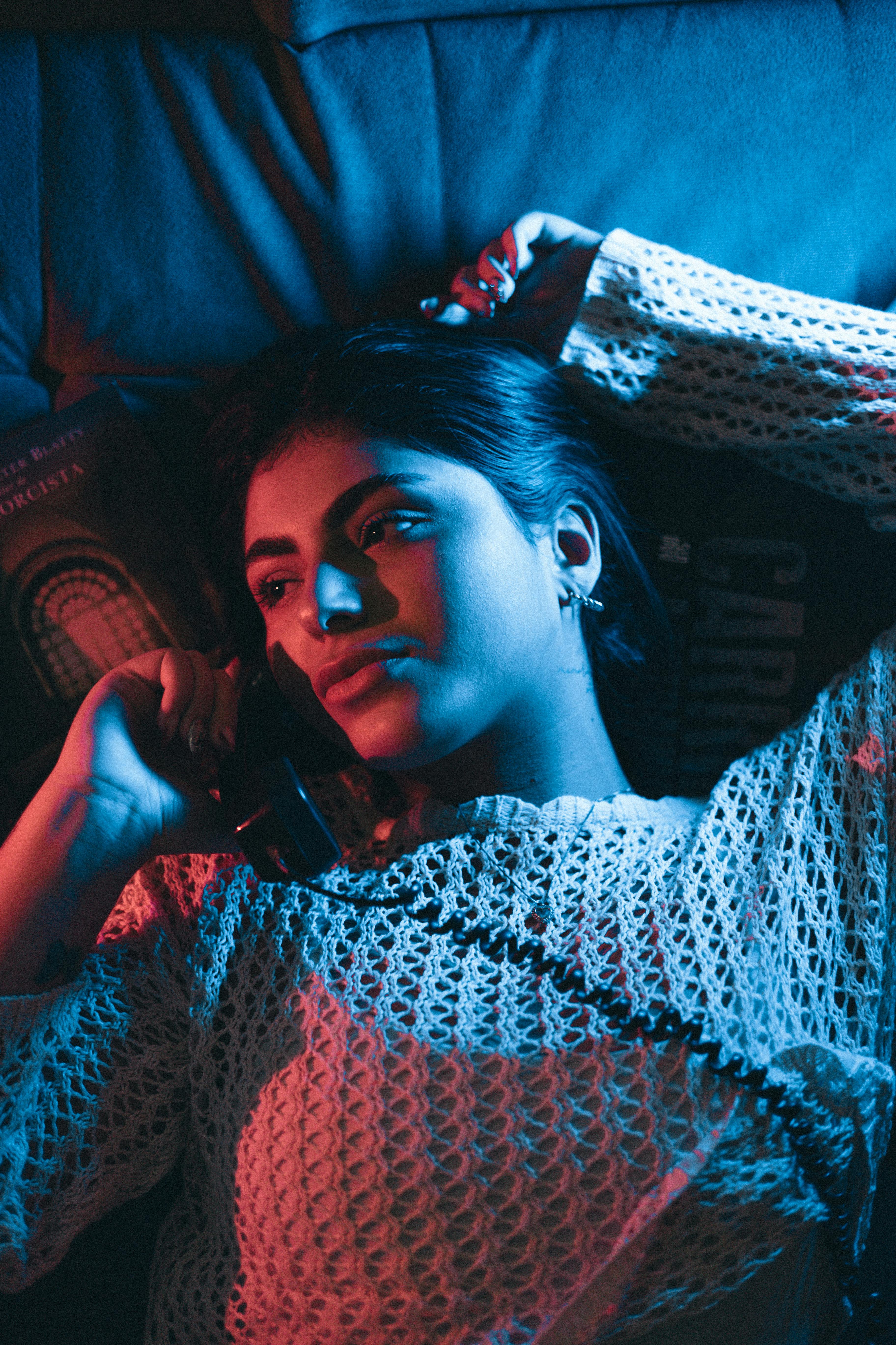 A woman lies on a couch with artistic red and blue lighting, creating a cinematic feel.