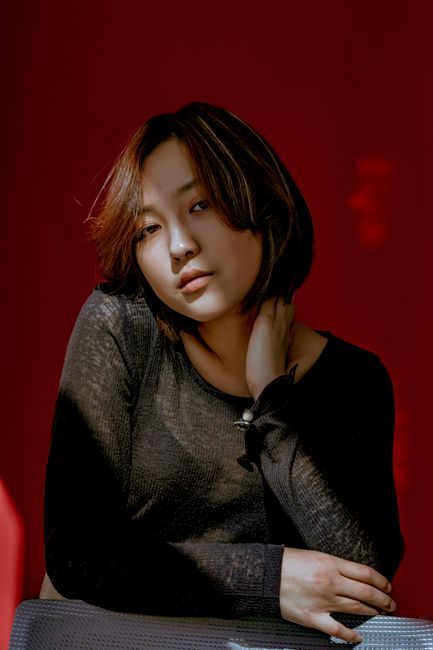 Stylish portrait of a woman against a bold red backdrop, showcasing modern casual fashion.