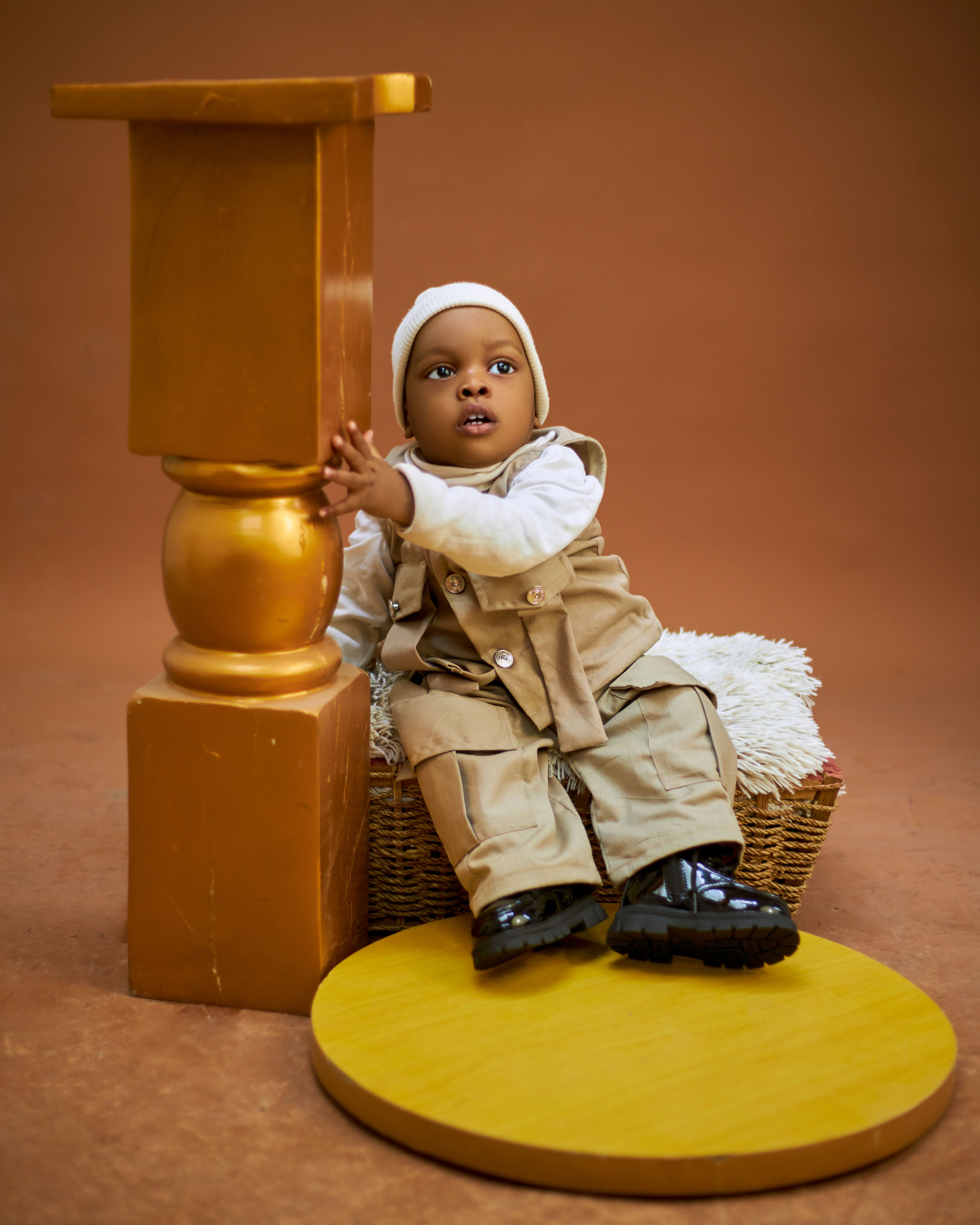 Charming portrait of a baby boy in beige attire with a warm brown background. Perfect stock photo for family and fashion themes.