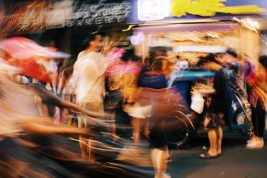 Abstract motion blur of people in a vibrant night street market.