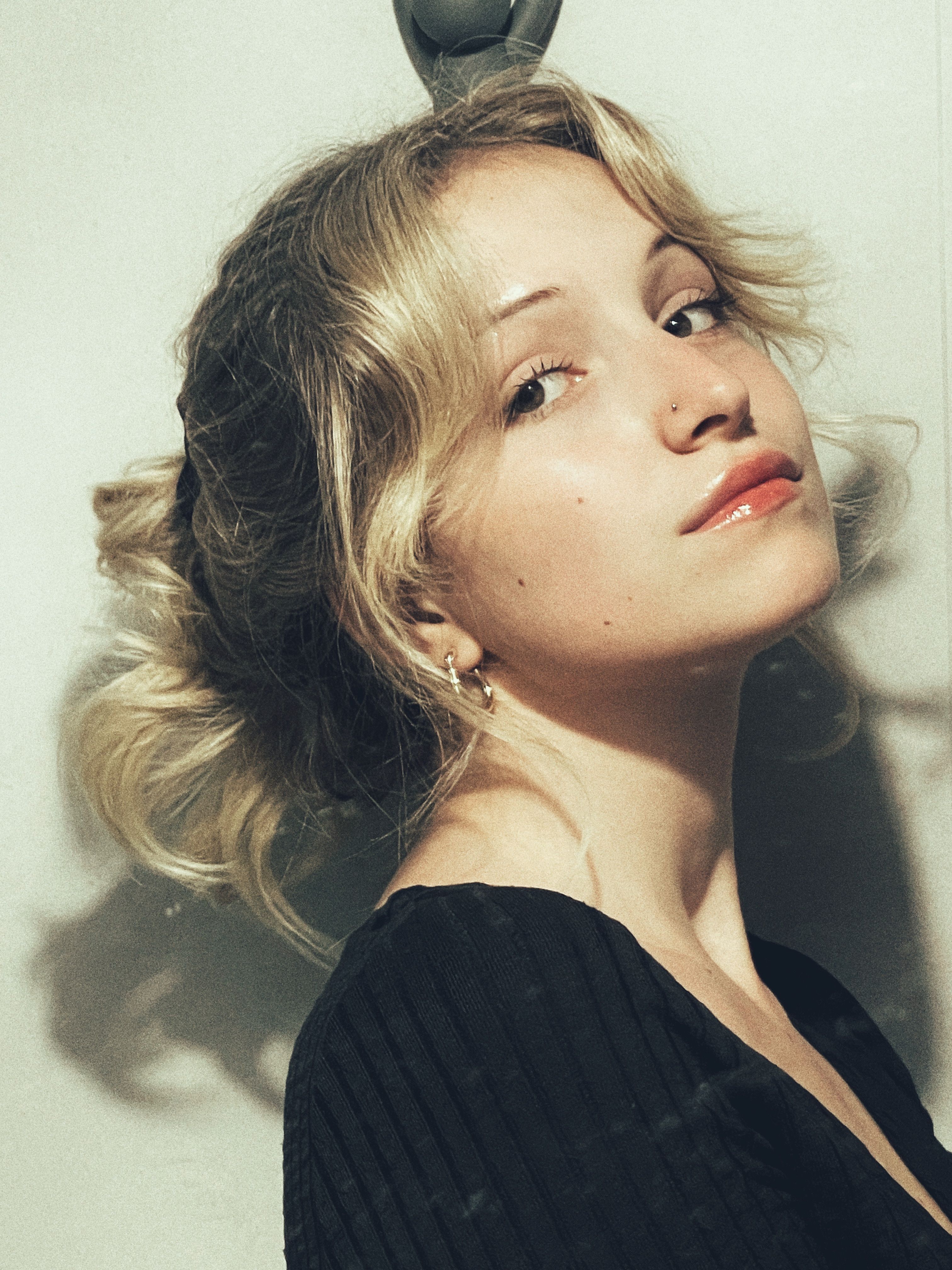 Portrait of a young woman with curly hair in a soft light setting, exuding elegance.